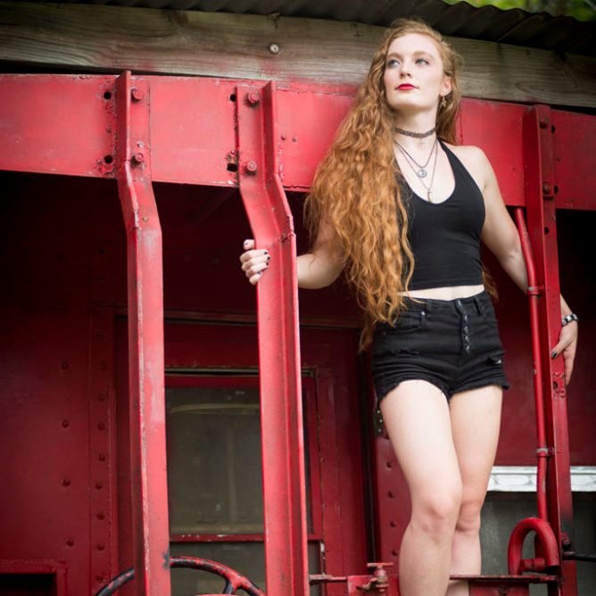 Photo of Nicole Korolevich in black posing on a caboose